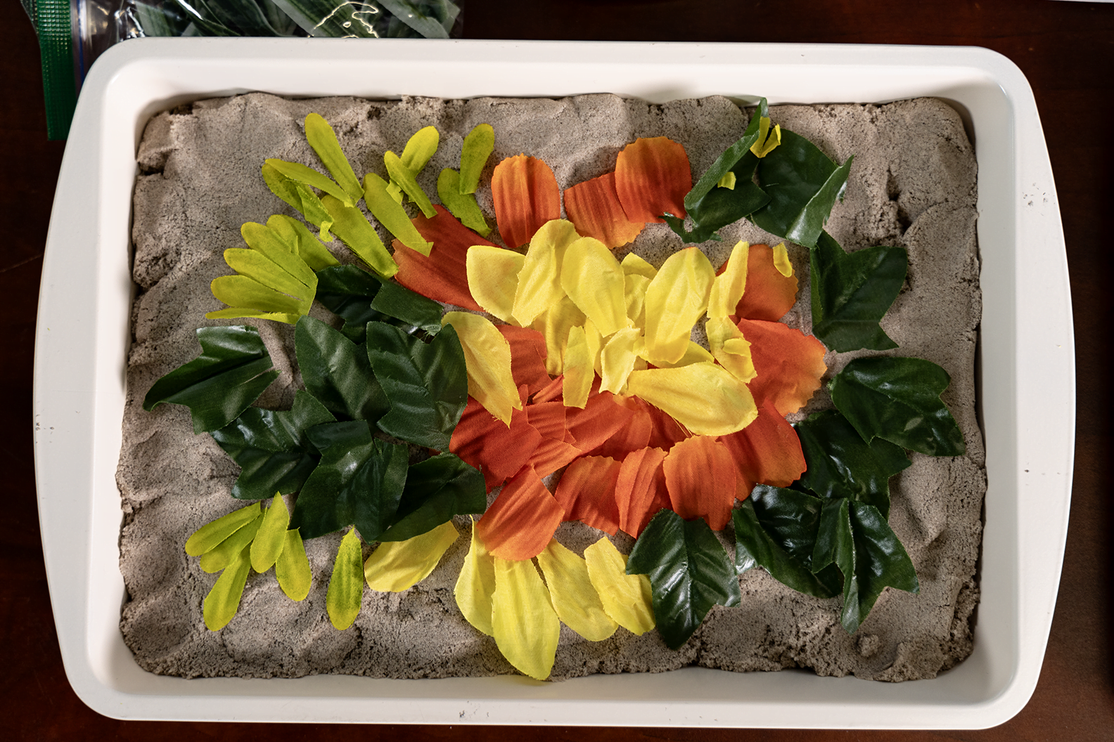 Environmental art using kinetic sand and flowers.